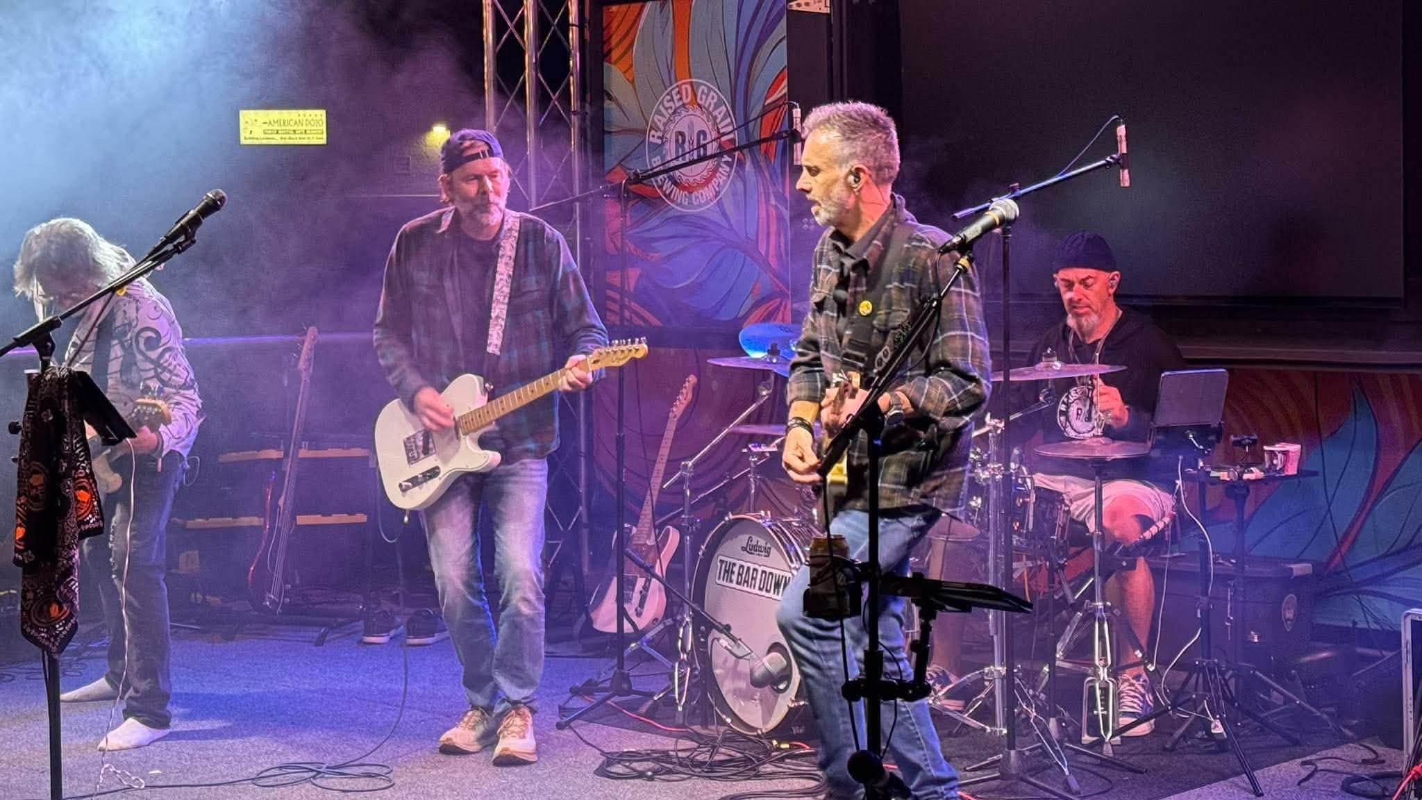 The Bar Downs performing together under purple and white stage lights